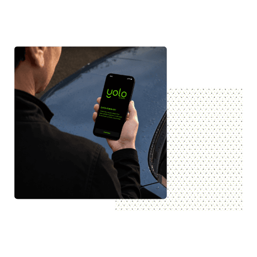 A traveler booking a Yolo car rental from a phone beside a car